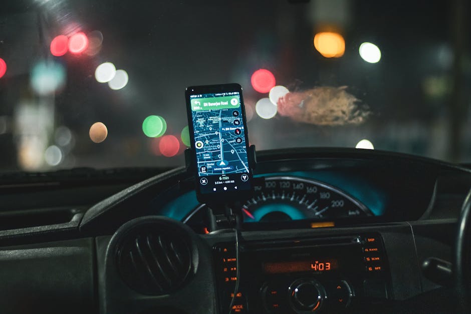 Close-up of a smartphone with map navigation in a car at night with bokeh effect.