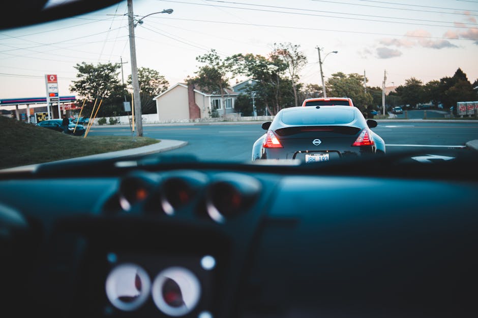 Automobile riding on rural asphalt road near houses and green trees through glass