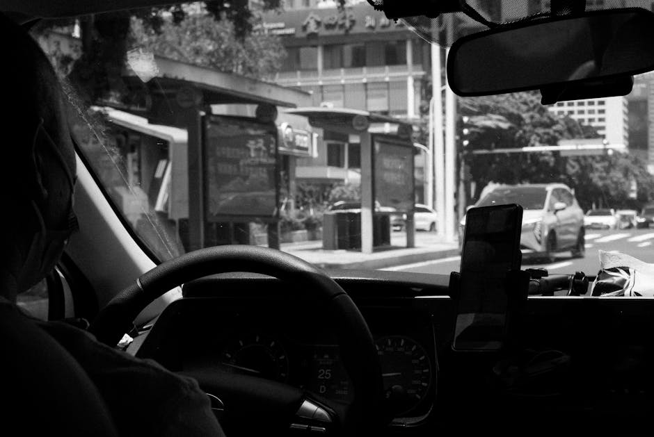 Monochrome photo of a taxi driver navigating a city street in broad daylight.