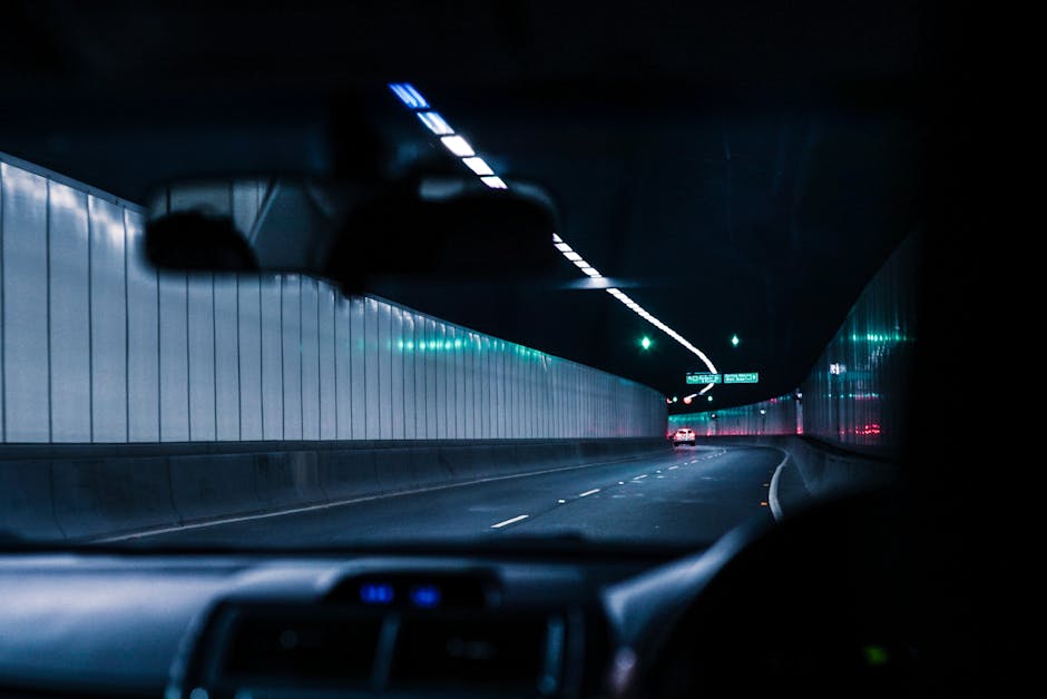 Inside view of a car driving through a brightly lit urban tunnel at night, showcasing modern transportation.